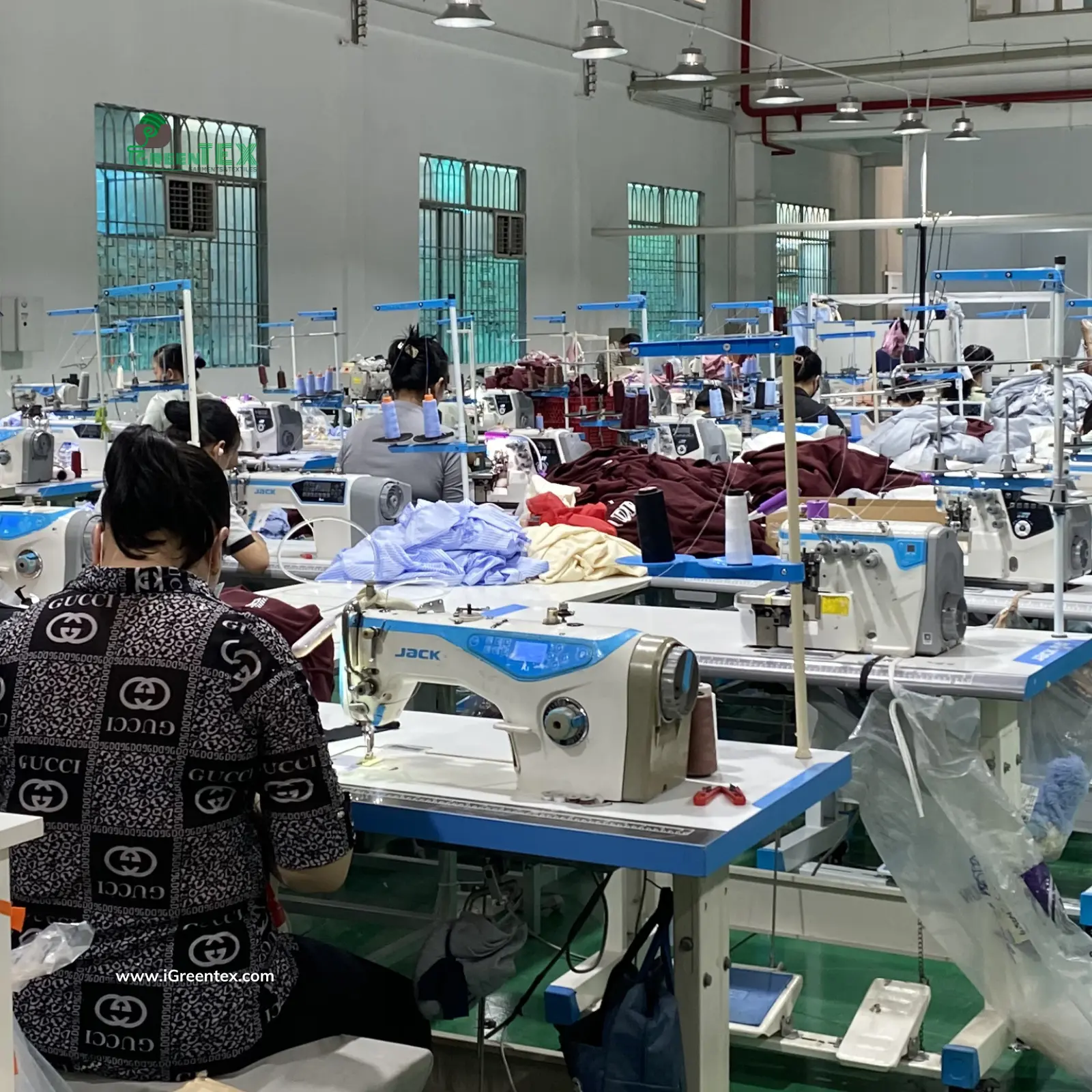 Skilled workers at iGreen Tex Vietnam performing technical checks and garment sampling on a specialized sewing line to ensure production accuracy.