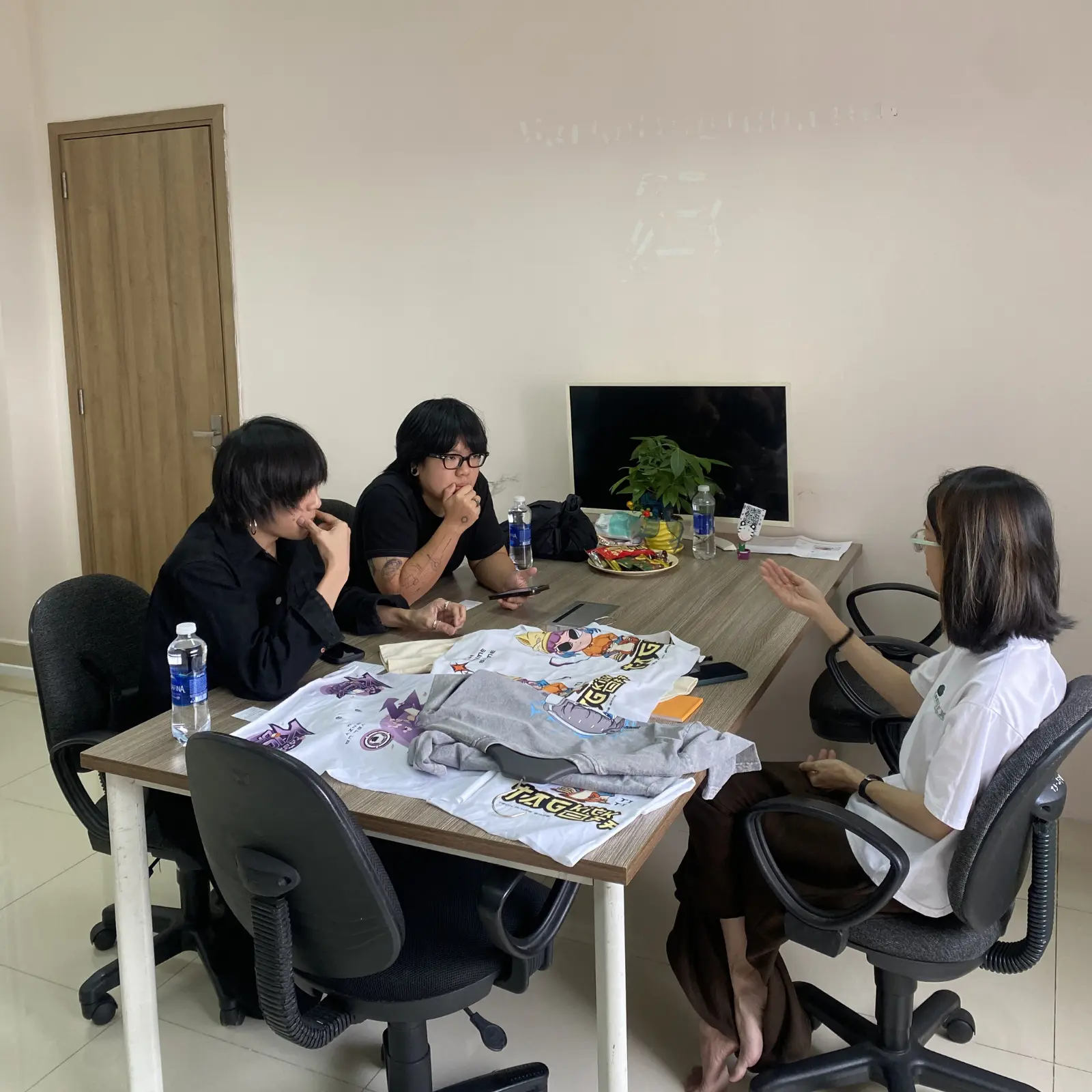 A professional clothing manufacturer business meeting at iGreen Tex Vietnam, featuring a face-to-face technical consultation with Japanese clients to discuss garment samples and export quality standards.