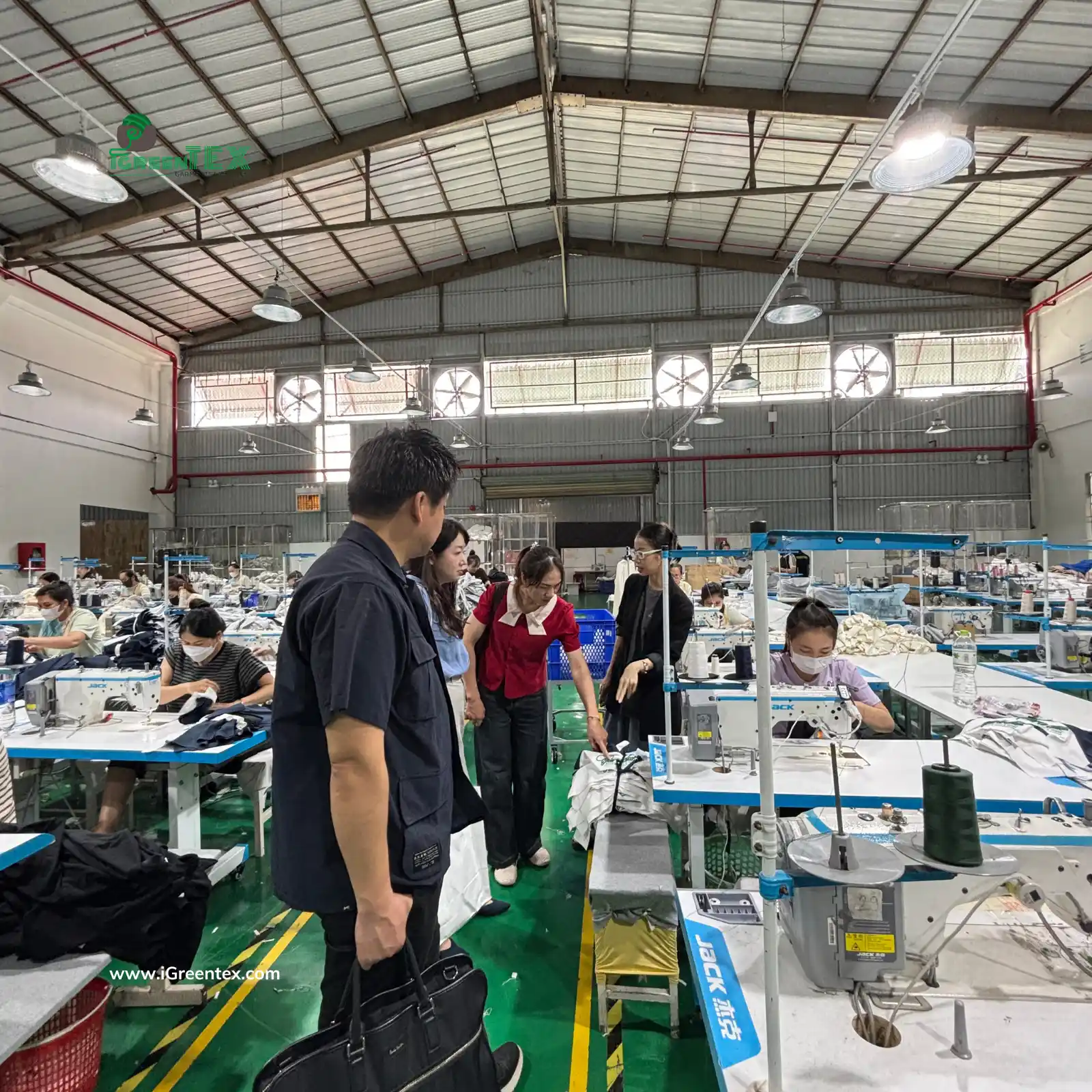 A professional scene at iGreen Tex Vietnam factory where Japanese clients are conducting an on-site quality inspection of a garment order. This demonstrates why iGreen Tex is trusted among clothing manufacturers in vietnam for japanese brands, adhering to strict Japanese AQL standards.